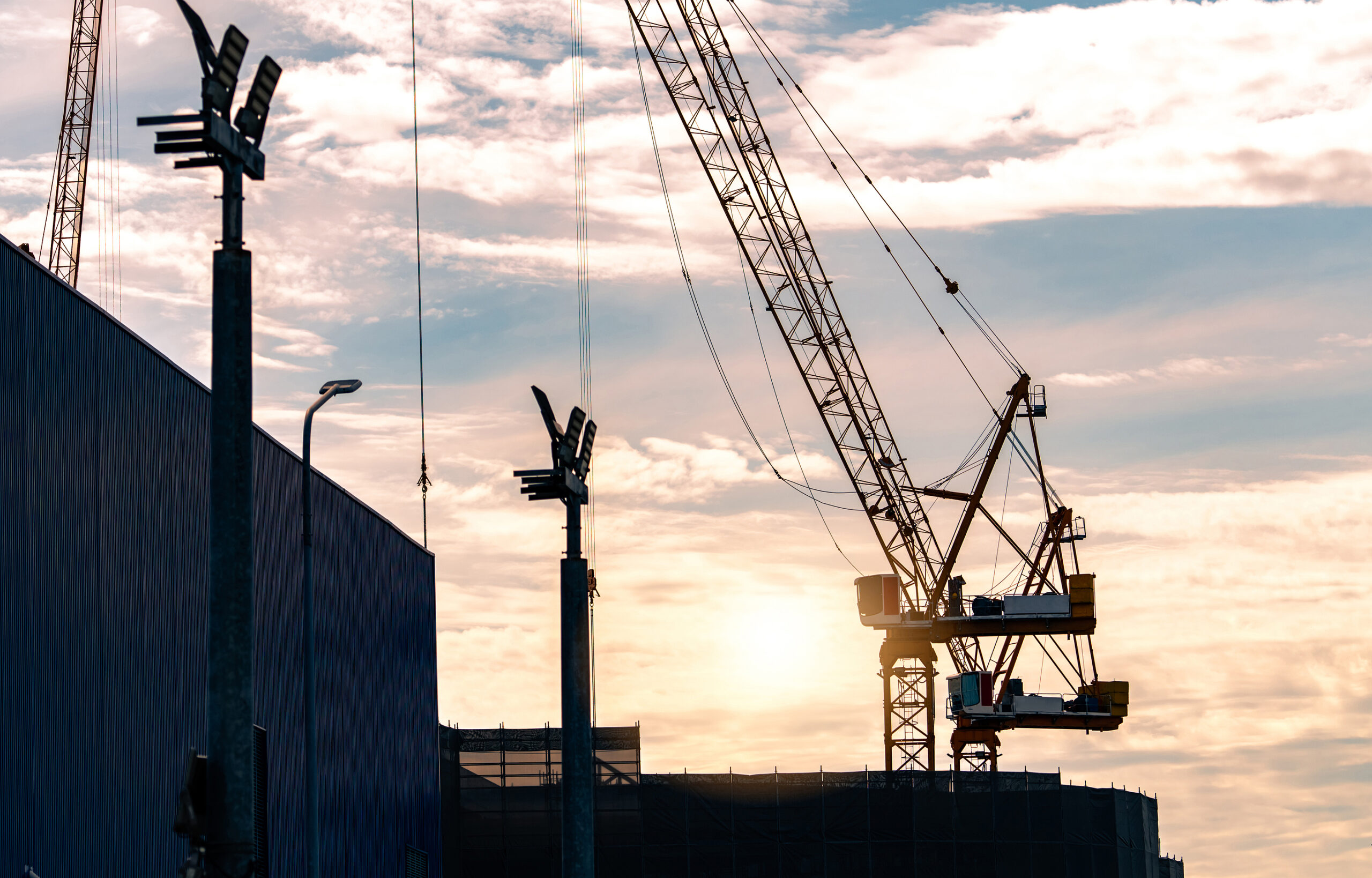 Silhouette construction crane against sunset sky. Crane use reel lift up equipment in construction site. Crane for rent concept. Crane dealership for construction business. Real estate industry.